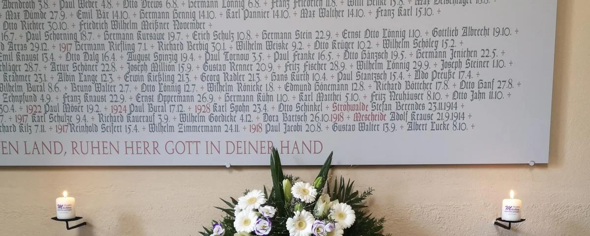 Gedenktafel in Gräfenhainicher Kirche mit einem Kranz davor.