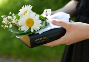 Konfirmandin mit Gesangbuch und Blumen.