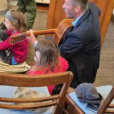 Diakon Guido Merten singt mit den Kindern und begleitet das Lied mit der Gitarre.  Andrea Schulze